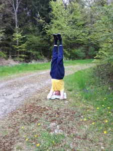Daniel im Kopfstand auf einer Wiese im Wald