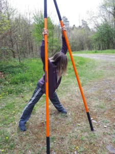 Frau hält zwei Stäbe und beugt sich zur Seite